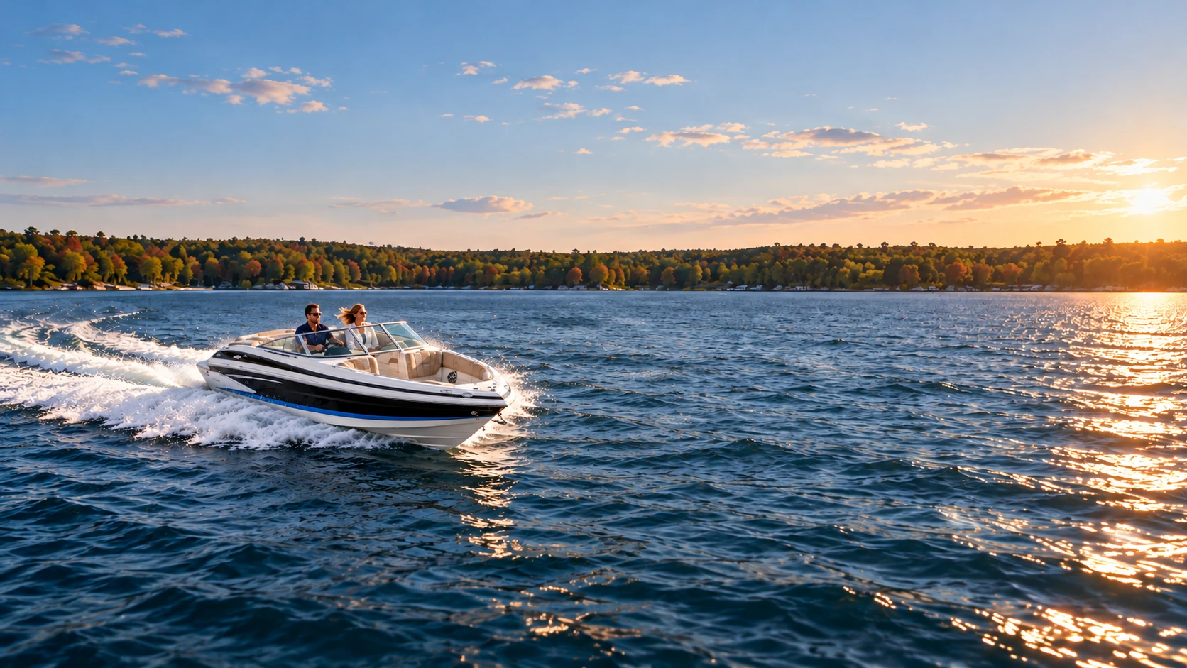 A husband and wife driving a Crownline 220 SS across the lake with a distant forested shoreline